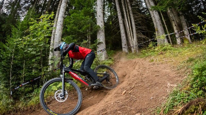 GasGas EEC 6 being ridden at a round of the UCI E-Enduro World Cup racing series. Rider exiting wooded section onto lightly banked trail section