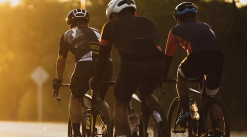 Strava hero image of 3 road riders in group riding toward the sun